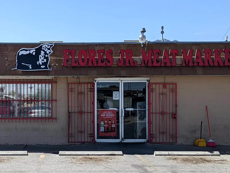 The Flores Jr. storefront by day: the bull sign, red letters and red iron bars.