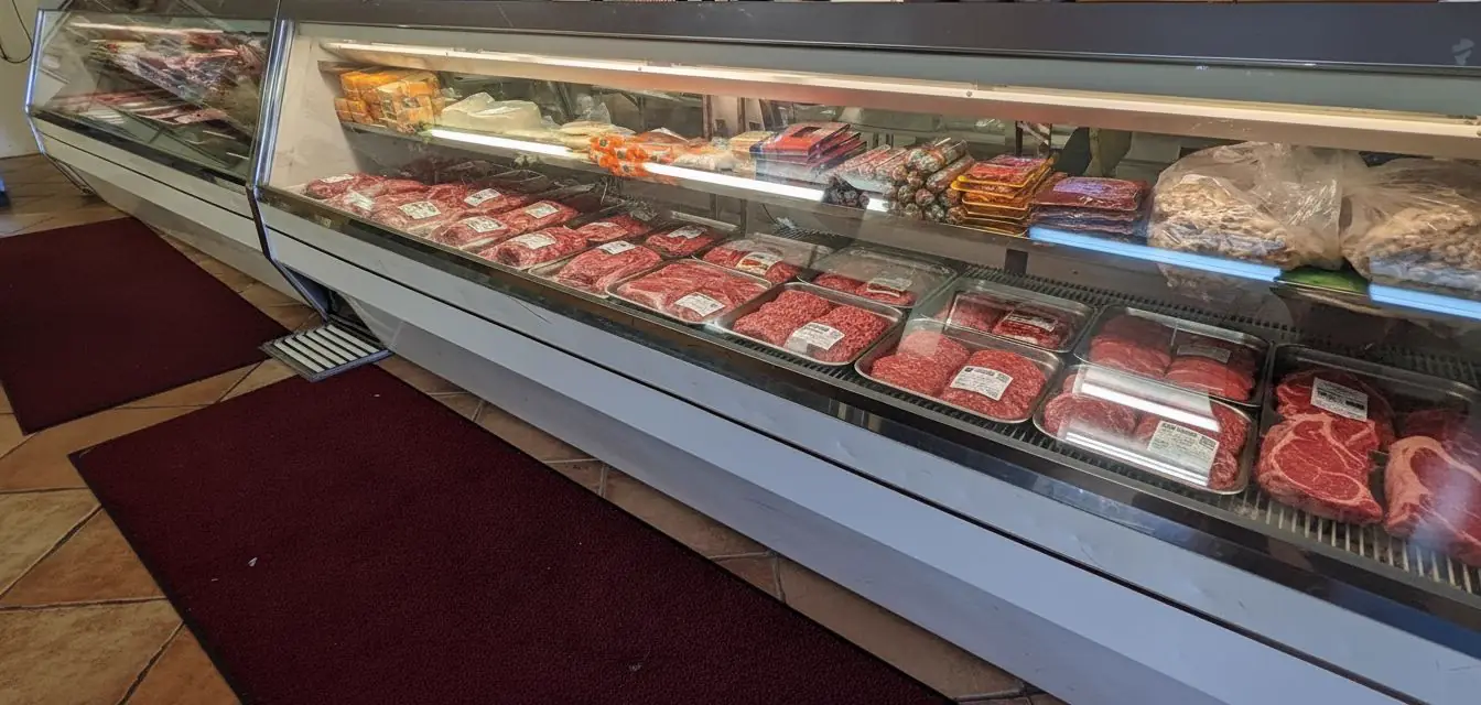 The long glass meat case at Flores Jr., full of trays of fresh cuts.