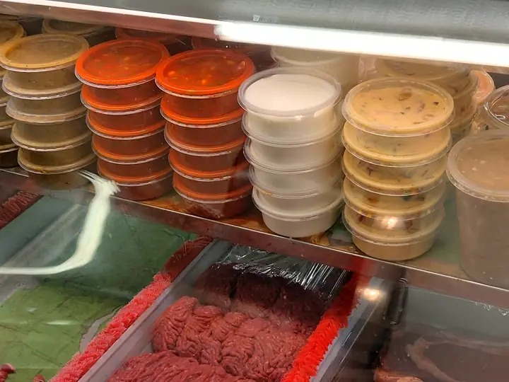 Stacks of salsa, crema, chile con queso and beans in deli tubs at Flores Jr.